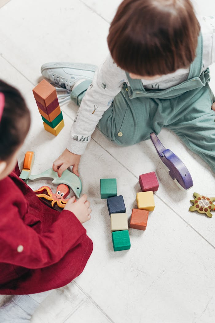 about-02 Two young children playing with colorful wooden blocks indoors, fostering creativity and fun.