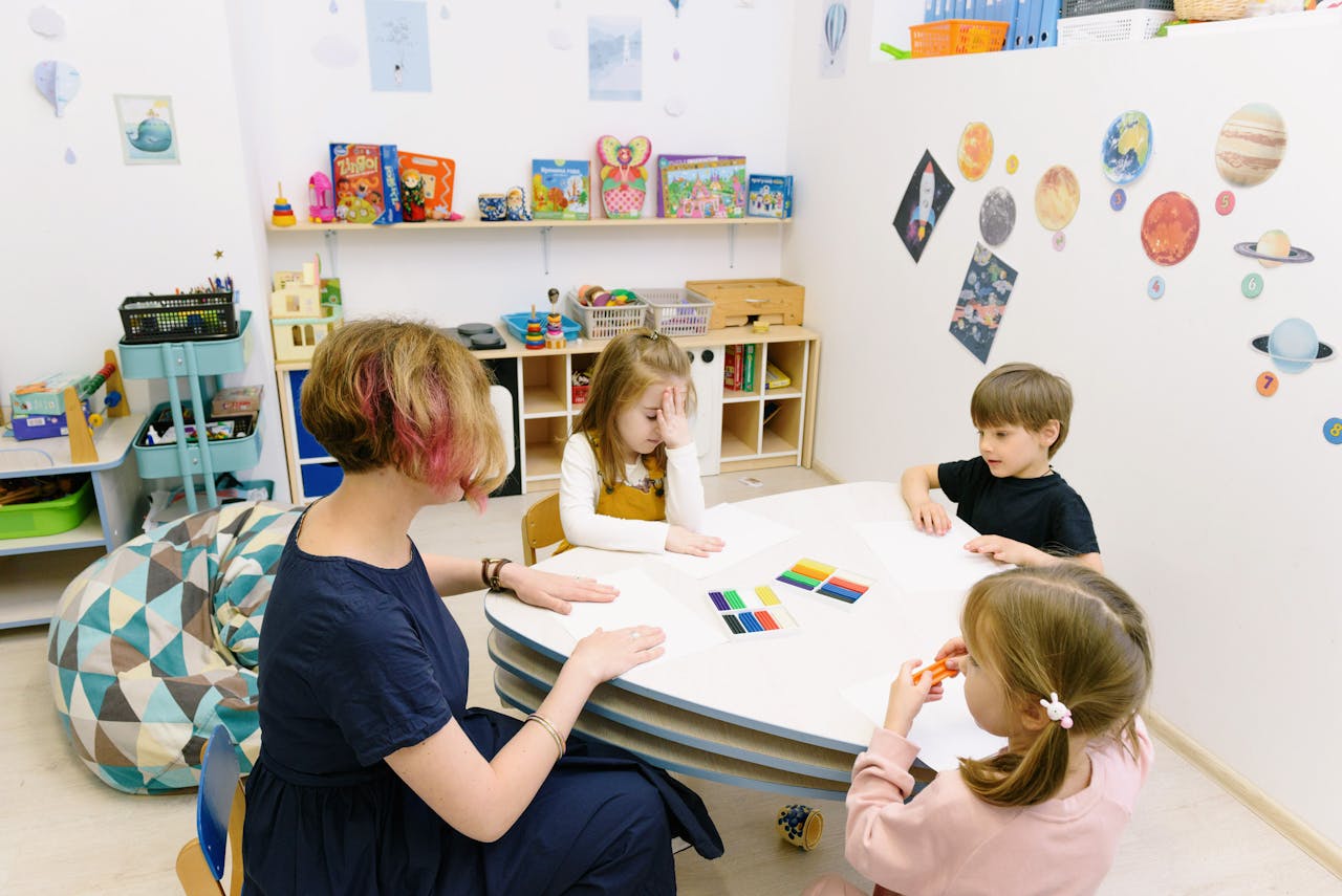 services-03 Children engage in a colorful activity with a teacher in a bright kindergarten classroom.